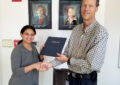 Smiling woman receives certificate from man