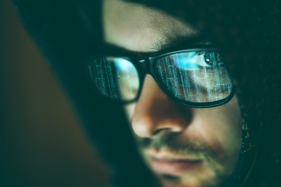 Man looking at computer screen reflected in his eye glasses.