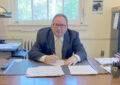 Smiling man sits at desk