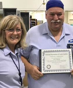 Two employees, one holding an award.