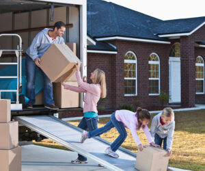Couple unloads boxes from moving van.