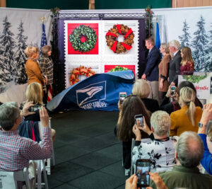 People stand on stage with oversized stamp image