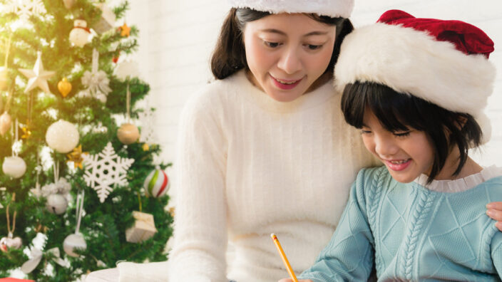 Woman watches as child writes letter to Santa.