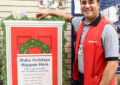 Smiling worker stands near holiday display inside Post Office lobby