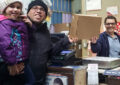 Smiling father with young daughter hand package to postal worker at retail counter