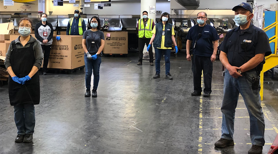 Postal employees standing in a USPS plant.