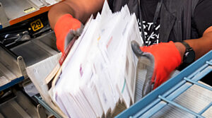 Postal worker handles stack of mail <a href=