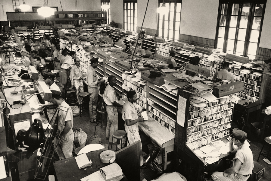 A black-and-white image of Black men sorting mail in a workroom