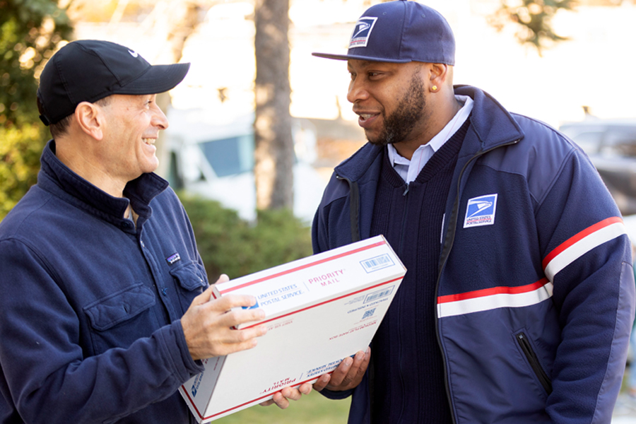 Man receives package from smiling letter carrier