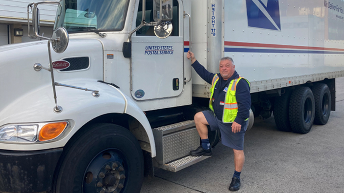 A man stands near a USPS tractor-trailer