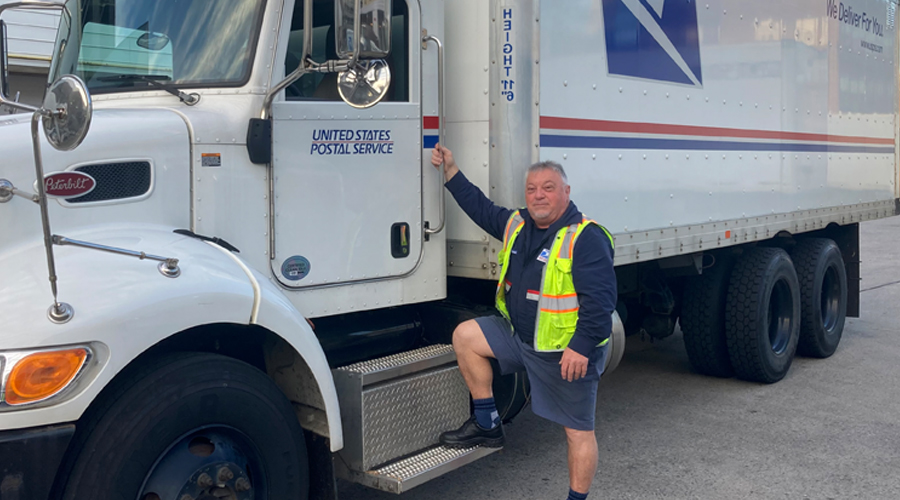 A man stands near a USPS tractor-trailer