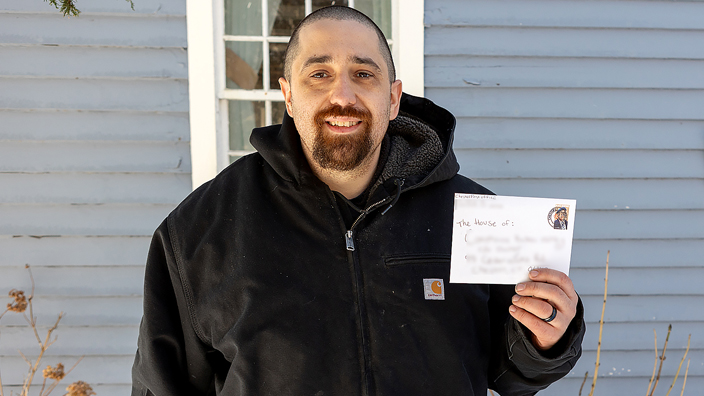 A smiling postal worker holds an envelope