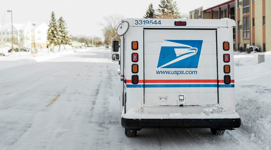 USPS delivery vehicle parked on side of snowy street