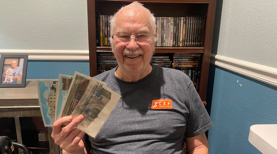 A smiling older man holds postcards