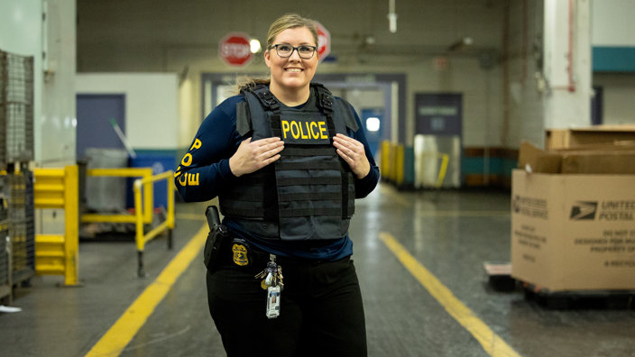 Smiling woman wearing a police vest stands in a work room
