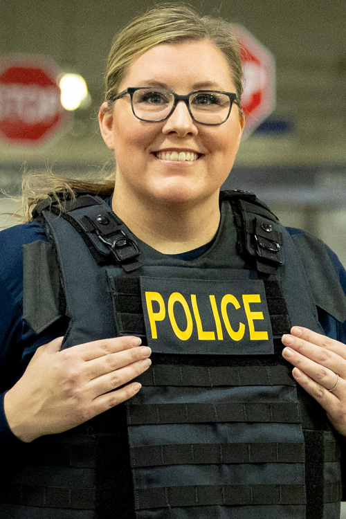 Smiling woman wearing police vest stands in a work room