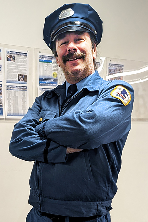 Smiling man wearing a vintage postal uniform, complete with cap