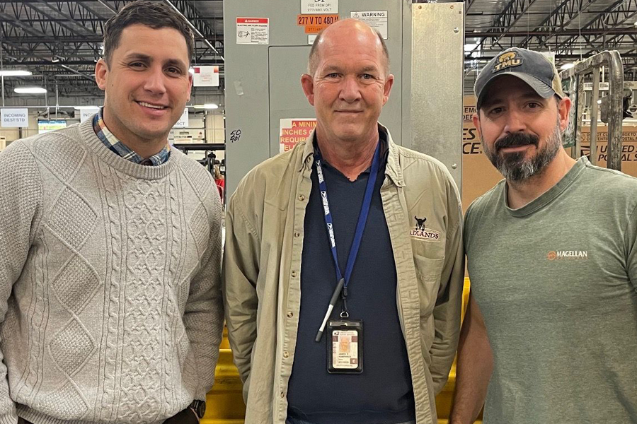 Three smiling men standing in a postal plant.