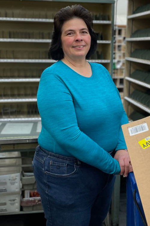 Smiling woman stands near mail cubby