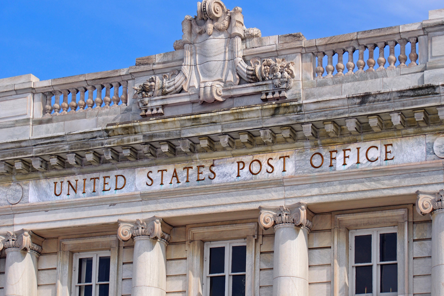 Close up of an ornate postal building that has windows and columns.