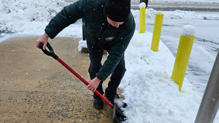 A Postal Service employee shovels snow off of a sidewalk