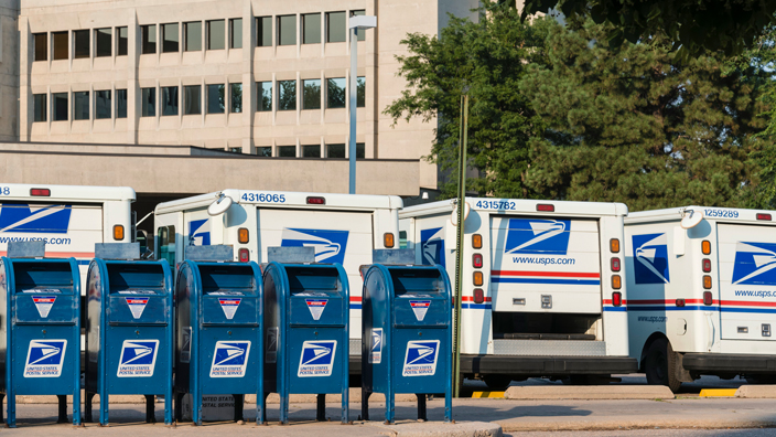 A row of postal vehicles and blue boxes