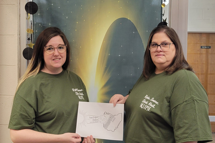Erin Sherwood, left, a Sycamore, OH, retail associate, and Postmaster Nicole Goist display Sherwood’s eclipse pictorial postmark design.
