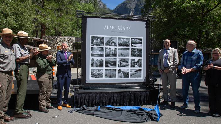 A group of participants unveiling the Ansel Adams stamp images