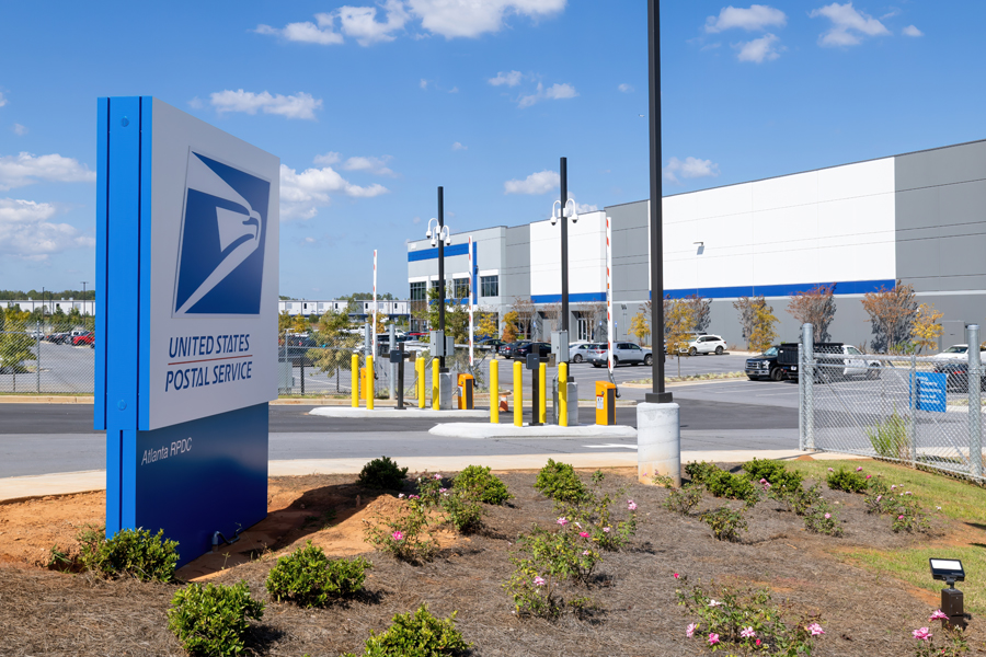 Sign with USPS logo near modern looking facility