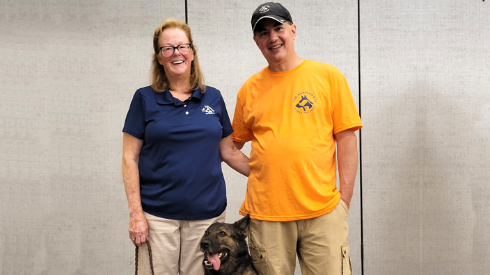 Cynthia Bahneman Herman and Jeff Herman stand with Dory, a service dog they are training.