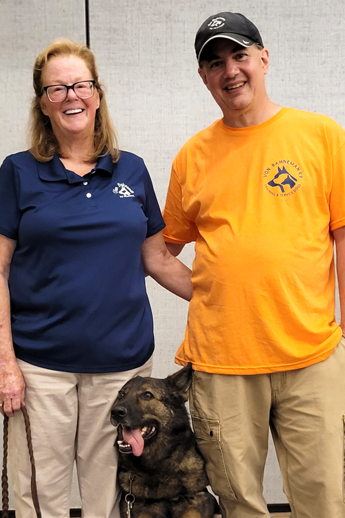 Cynthia Bahneman Herman and Jeff Herman stand with Dory, a service dog they are training.