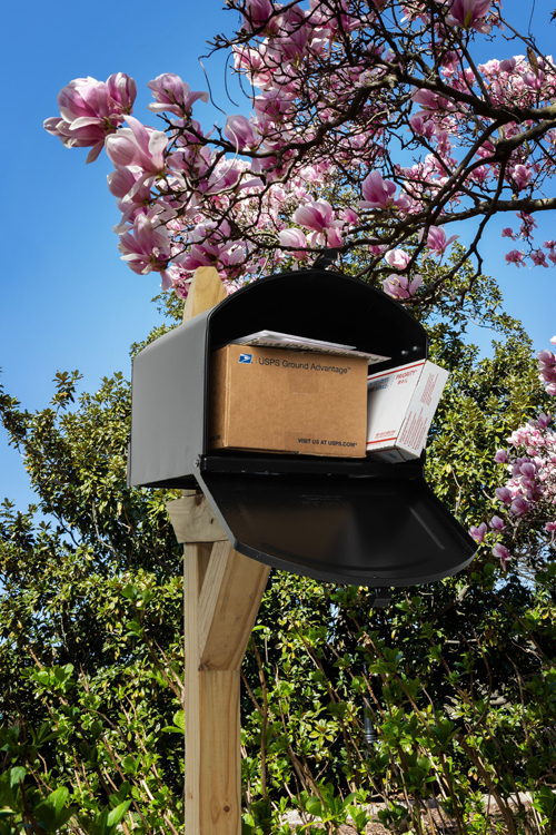 A dark gray mailbox containing two packages and letters.
