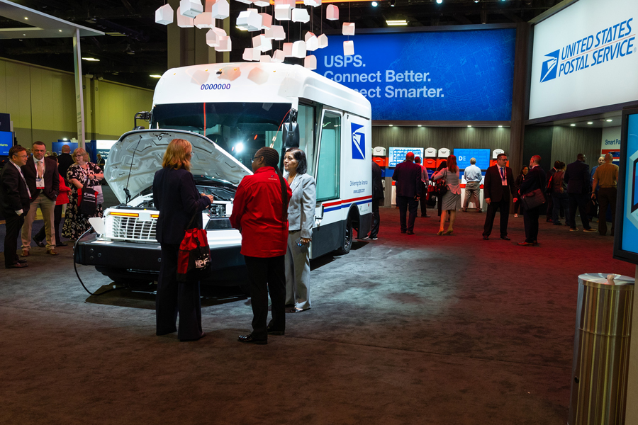 A group of people stand near a USPS next-generation delivery vehicle.