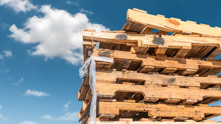 A stack of wooden pallets against the backdrop of a blue sky