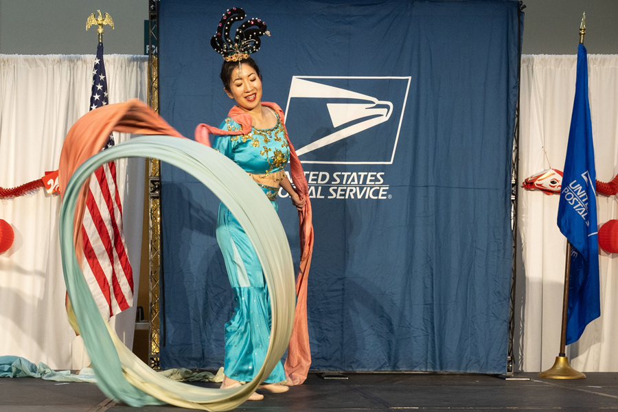 A woman of Asian ancestry dances in a blue traditional dress