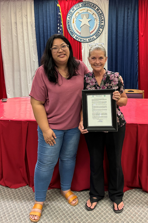 Rota Mayor Aubry Hocog, left, presents Tina Ramirez with a resolution honoring her service with USPS.