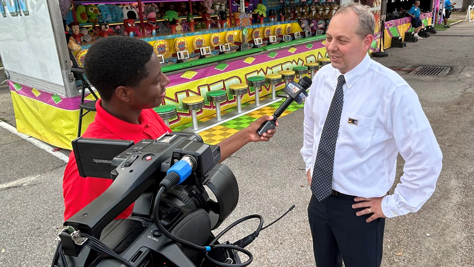 Biloxi, MS, Postmaster Ken Oglesbee is interviewed at the recent Carnival Nights stamp dedication ceremony.