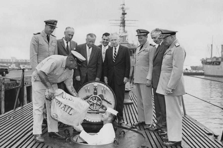Postmaster General Arthur E. Summerfield, fourth from left, looks on as mail is loaded onto the USS Barbero in Norfolk, VA, on June 8, 1959.
