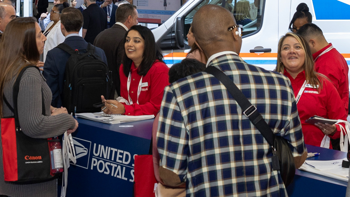 People gather around the USPS booth at the National Postal Forum.