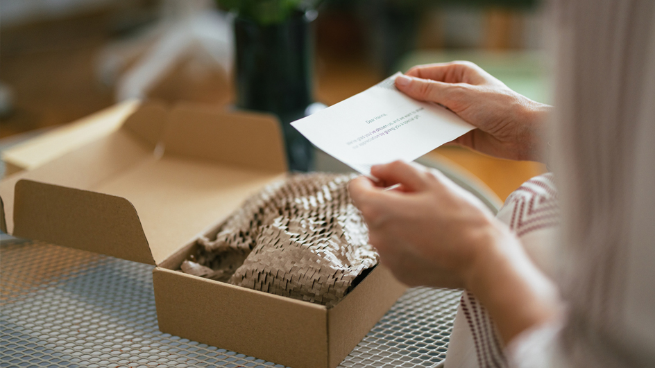 A woman opening the package and reading the card from a gift sender