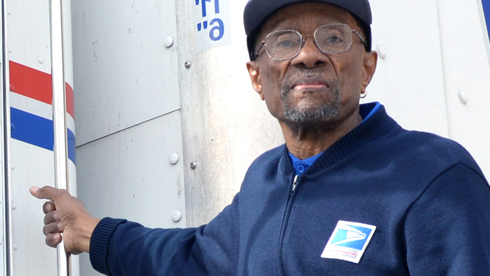 Carter Scott, a Gaithersburg, MD, tractor-trailer operator, stands next to a postal vehicle.