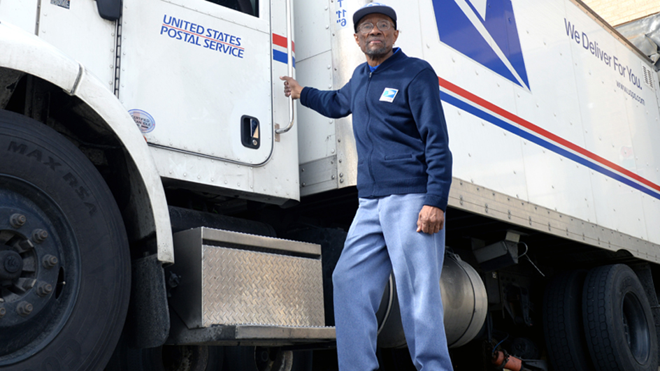 Carter Scott, a Gaithersburg, MD, tractor-trailer operator, stands next to a postal vehicle.