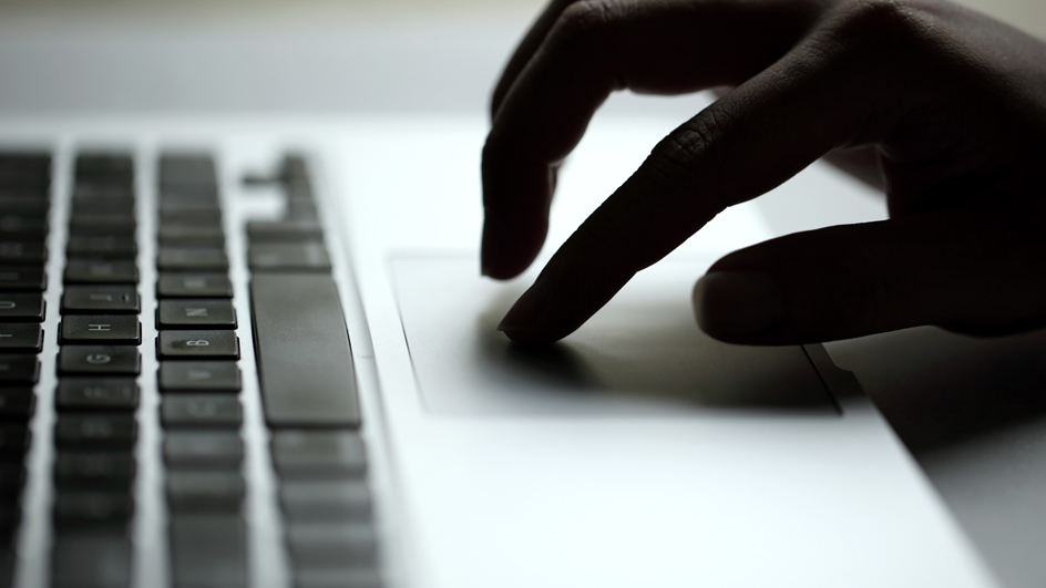 A close up of a computer user's fingers on the mouse of a keyboard