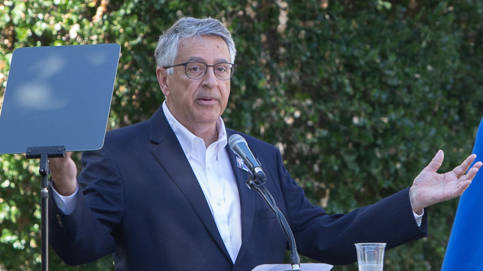 A man in a suit stand at a lectern