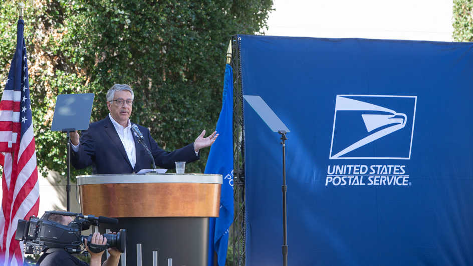 A man in a suit stand at a lectern