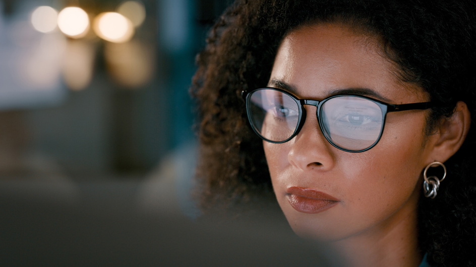 A woman wearing glasses peering a computer screen