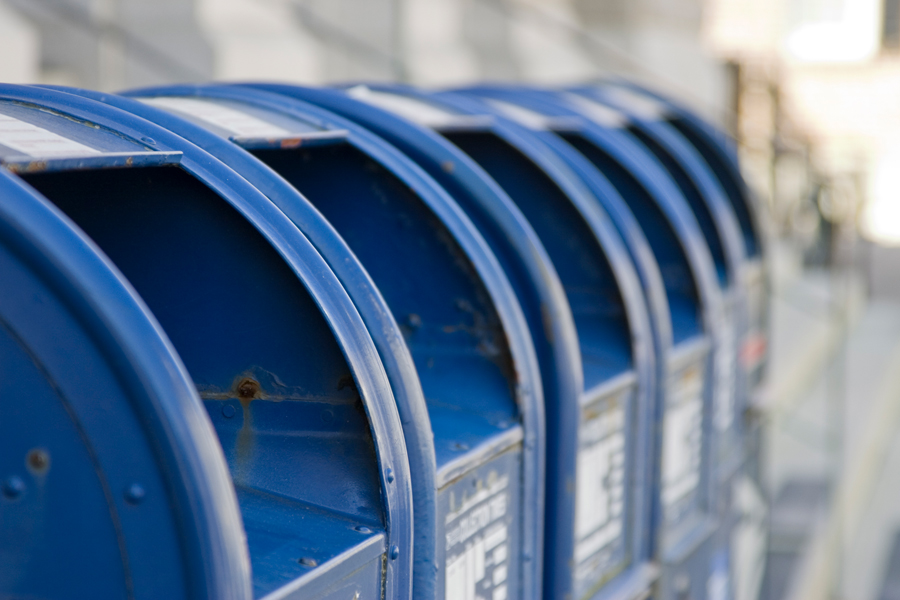 A row of USPS-branded blue boxes on a sidewalk