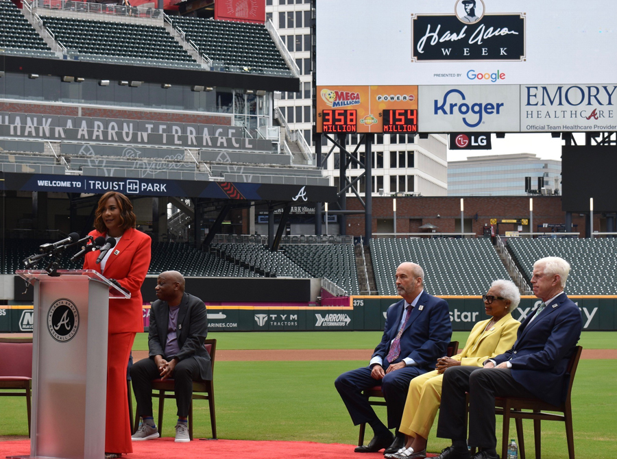 People in business wear sit on a baseball diamond during ceremony