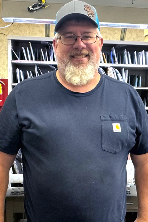 Smiling man stands in postal workroom