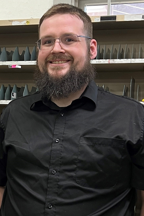 Smiling man stands in postal workroom